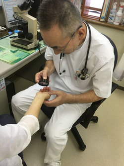 皮膚の診察を行う院長